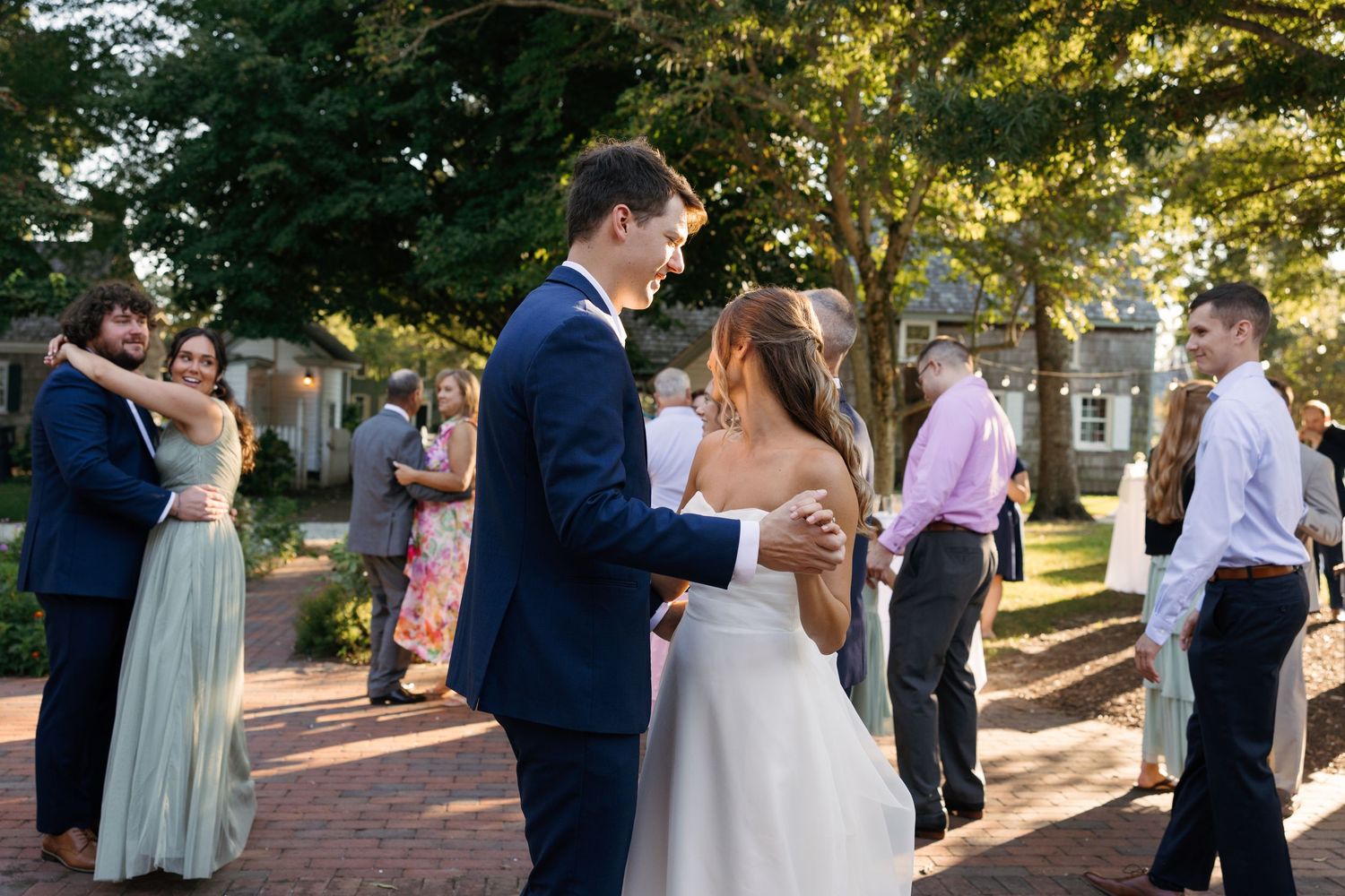 A wedding couple shares a romantic moment during their outdoor ceremony in a sunlit garden setting.