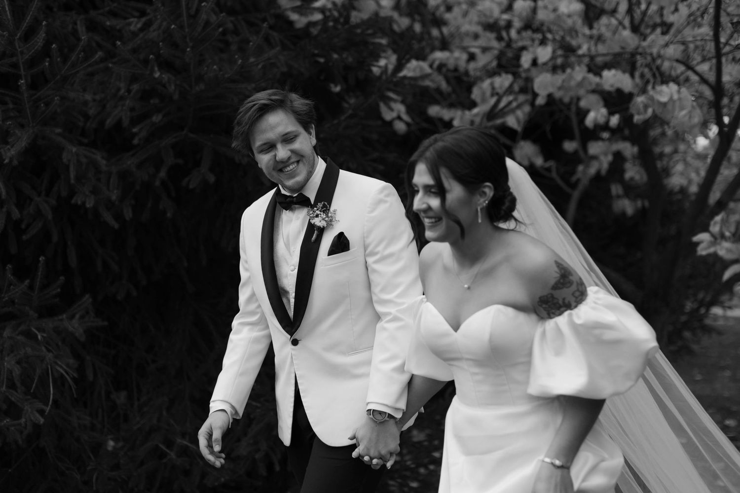 Couple in wedding attire dancing and laughing together outdoors.