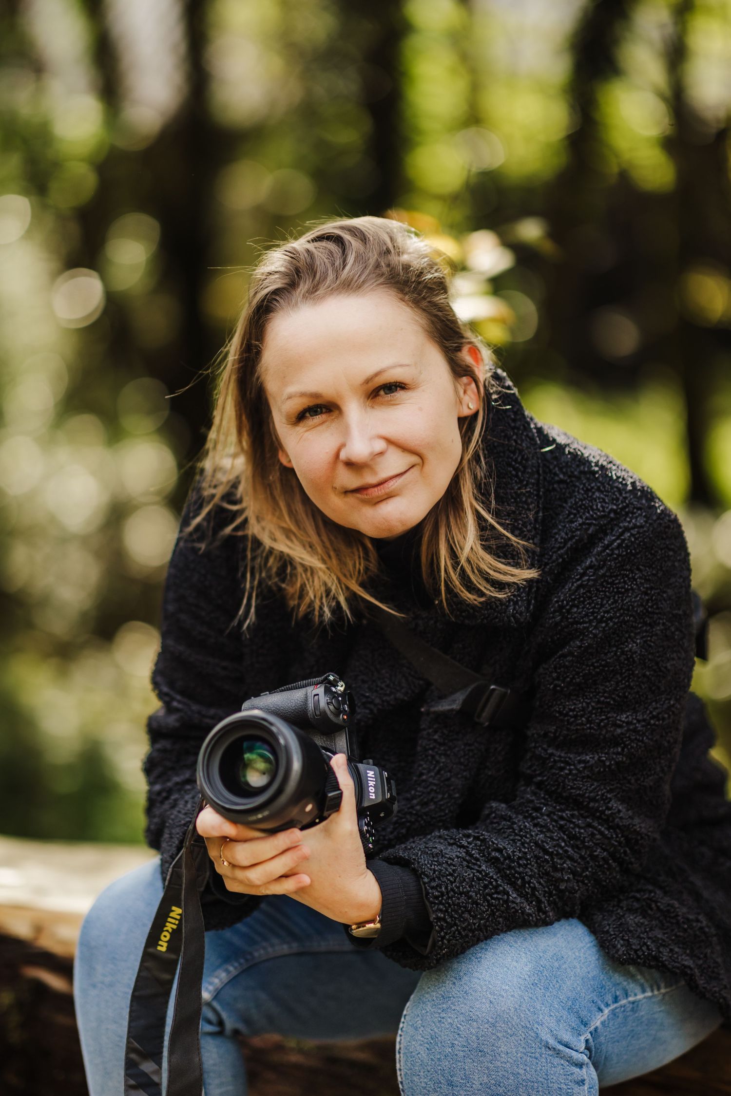 Paulina Kusa Photography holding her camera in the forest.