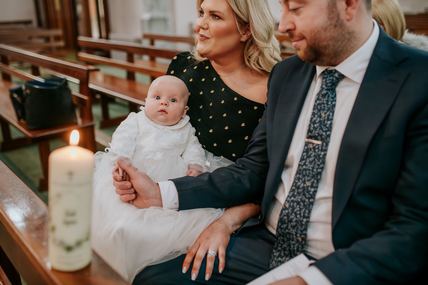 Father holding his baby son’s hand during christening, emotional family moment, baptism ceremony detail, natural christening photography.
