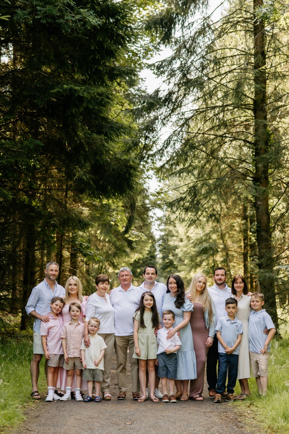 Large multigenerational family portrait on a forest path, with adults and children standing together in Center Parcs Longford