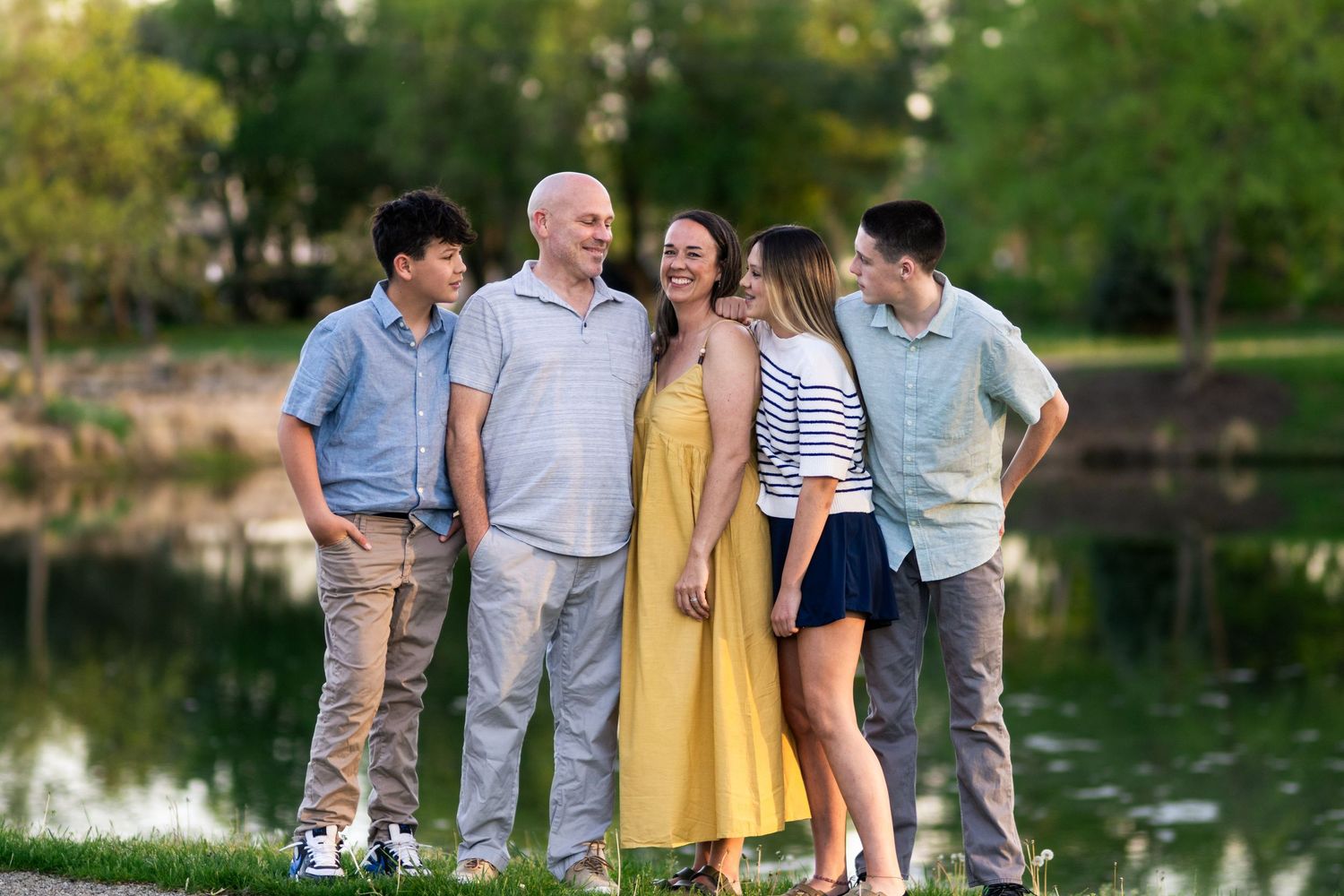 Family of four laughing together beside the water during a relaxed outdoor family photography session in Columbus, Ohio by Jamie Macey Photo