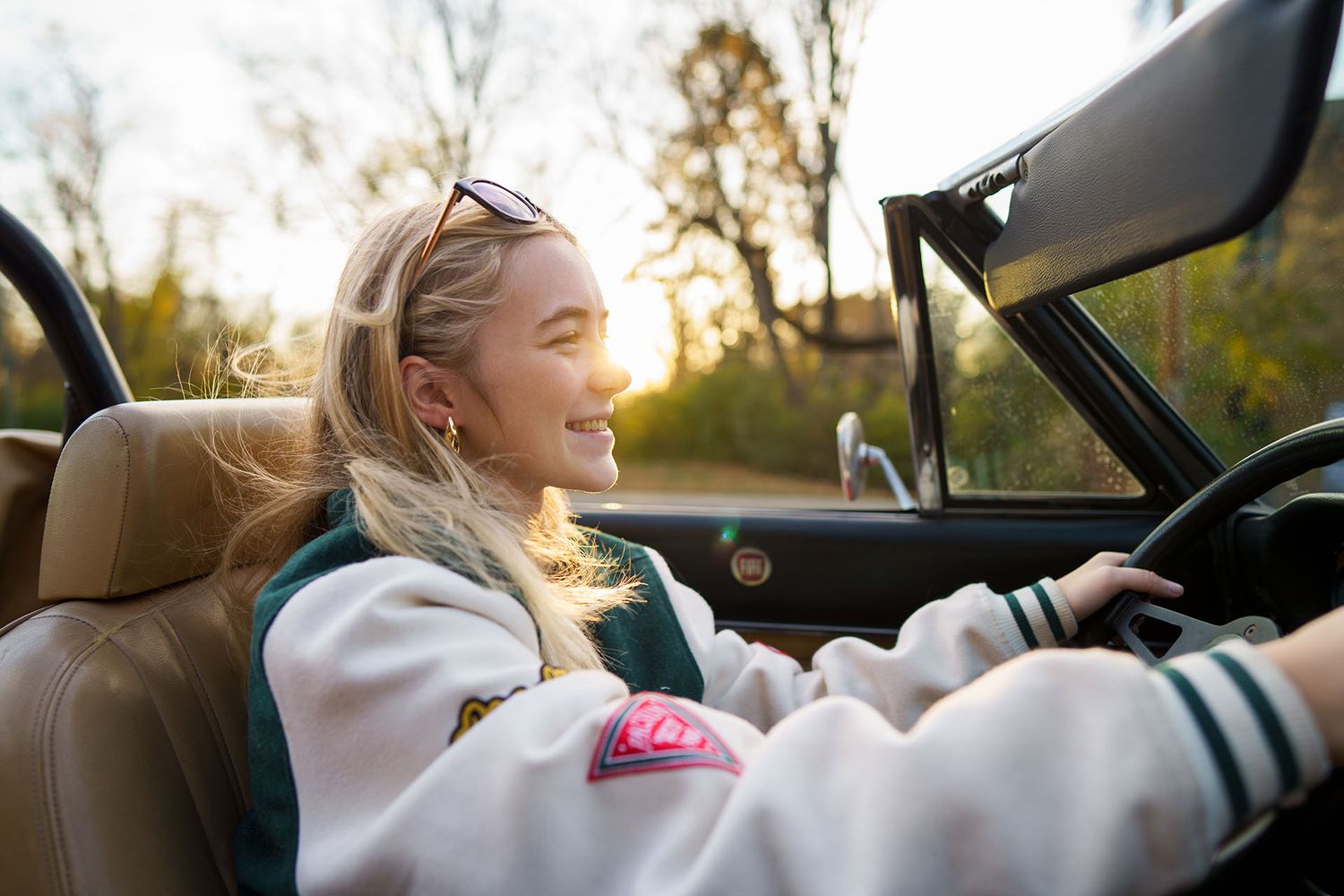Young girl smiling in the driver's seat of a vintage convertible during a fun portrait session at golden hour in Columbus, Ohio by Jamie Mac