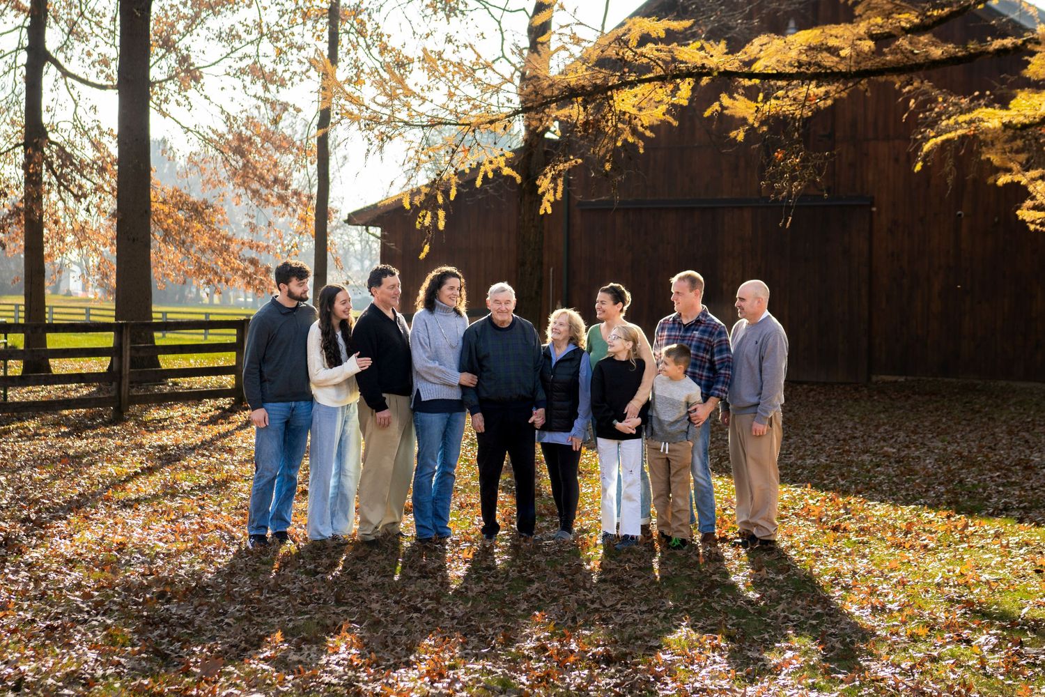 Extended family posing together outdoors in autumn with colorful trees and warm evening light in Columbus, Ohio by Jamie Macey Photography.