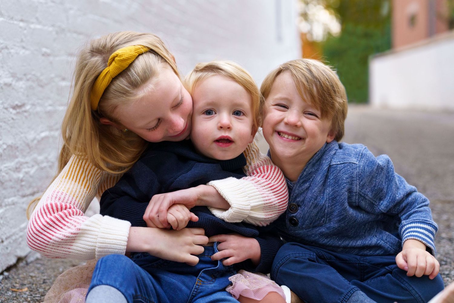 Sister hugging her two young siblings during a family session in Columbus, Ohio, photographed by Jamie Macey Photography