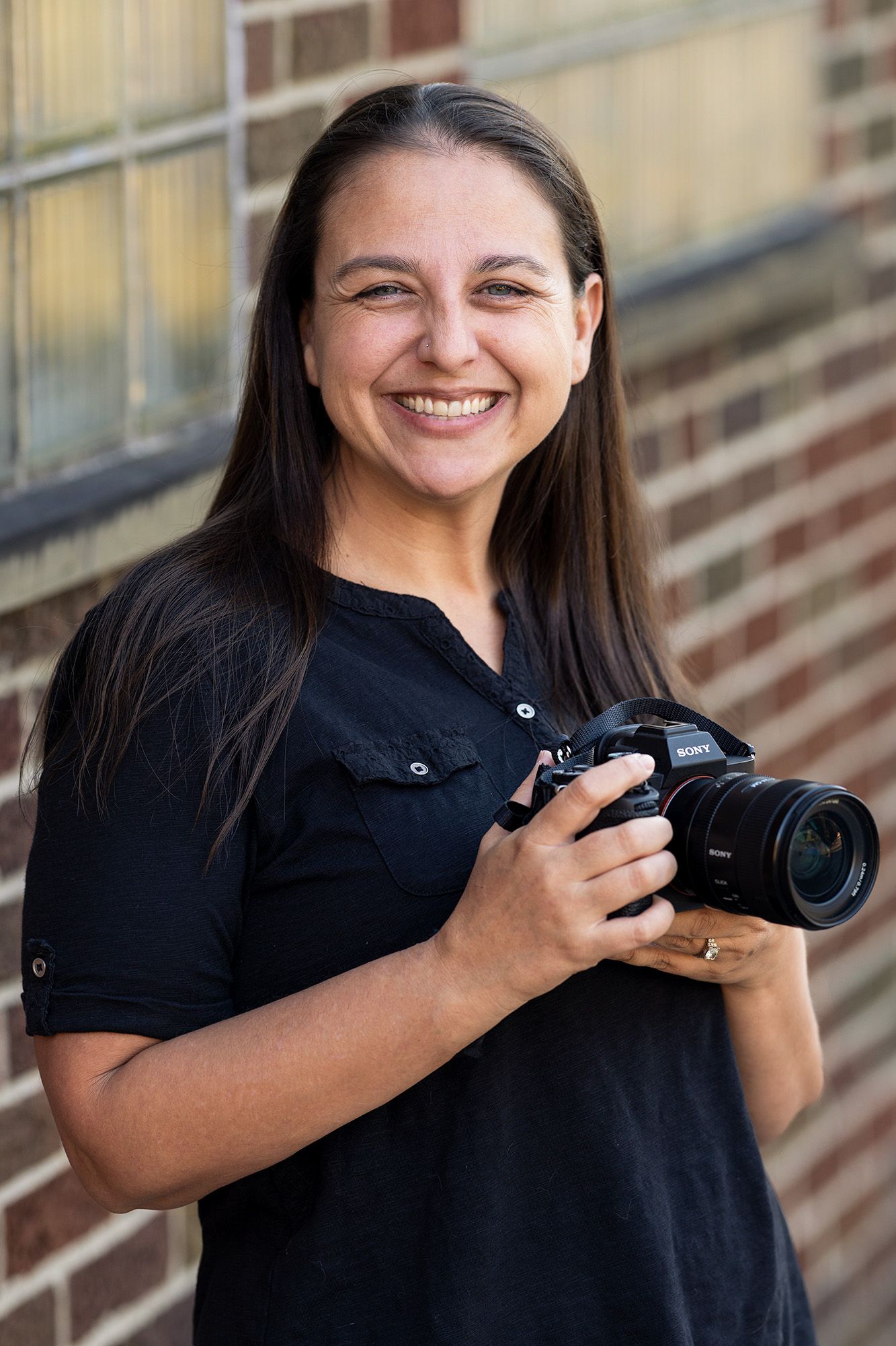 Professional female photographer holding a camera outdoors during a branding headshot session in Columbus, Ohio by Jamie Macey Photography.