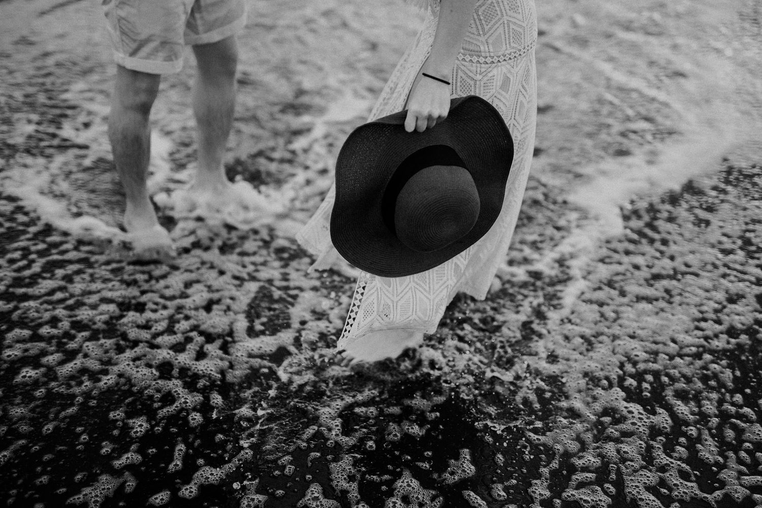 Close-up details of wedding shoes on textured beach sand.