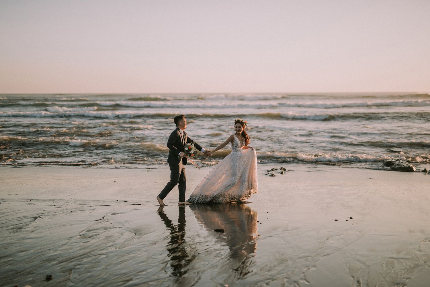 Romantic beach photoshoot at sunset with waves crashing in the background.