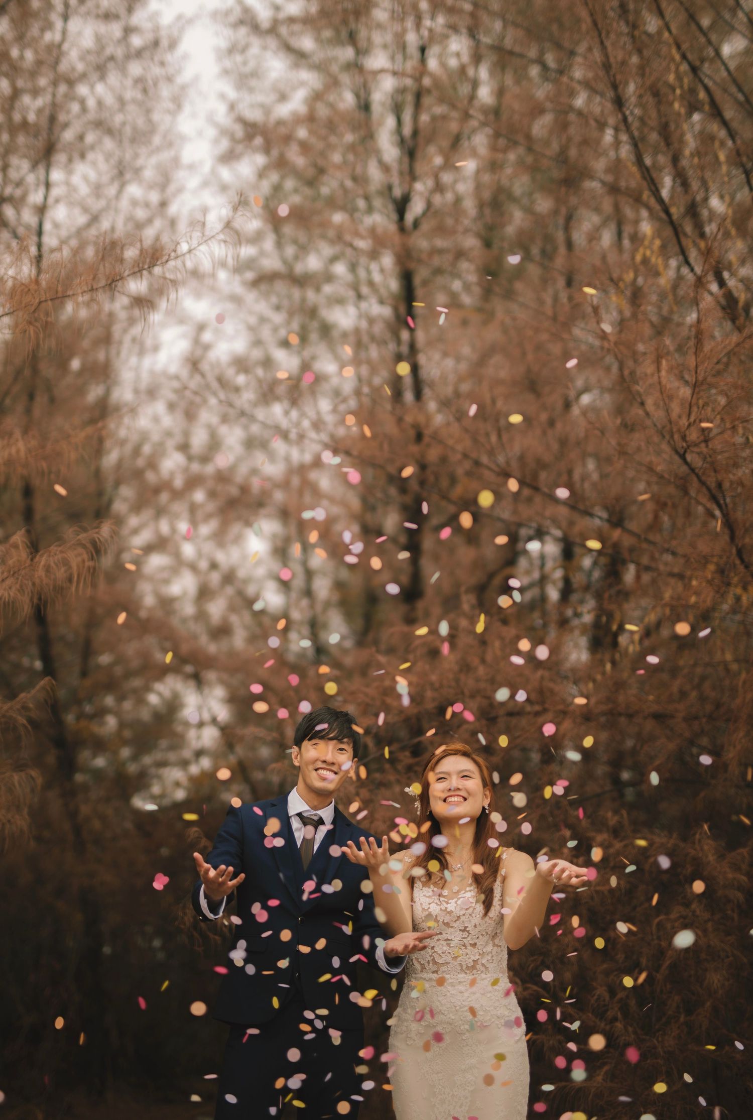 Joyful celebration with colorful confetti toss in autumn forest setting.