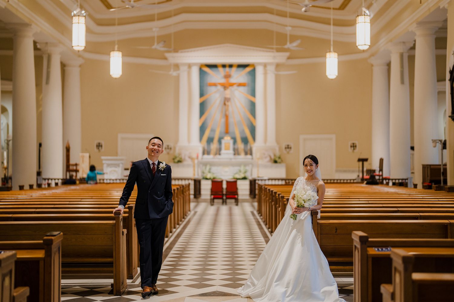 Wedding ceremony in an elegant church with checkered floors and classical columns.