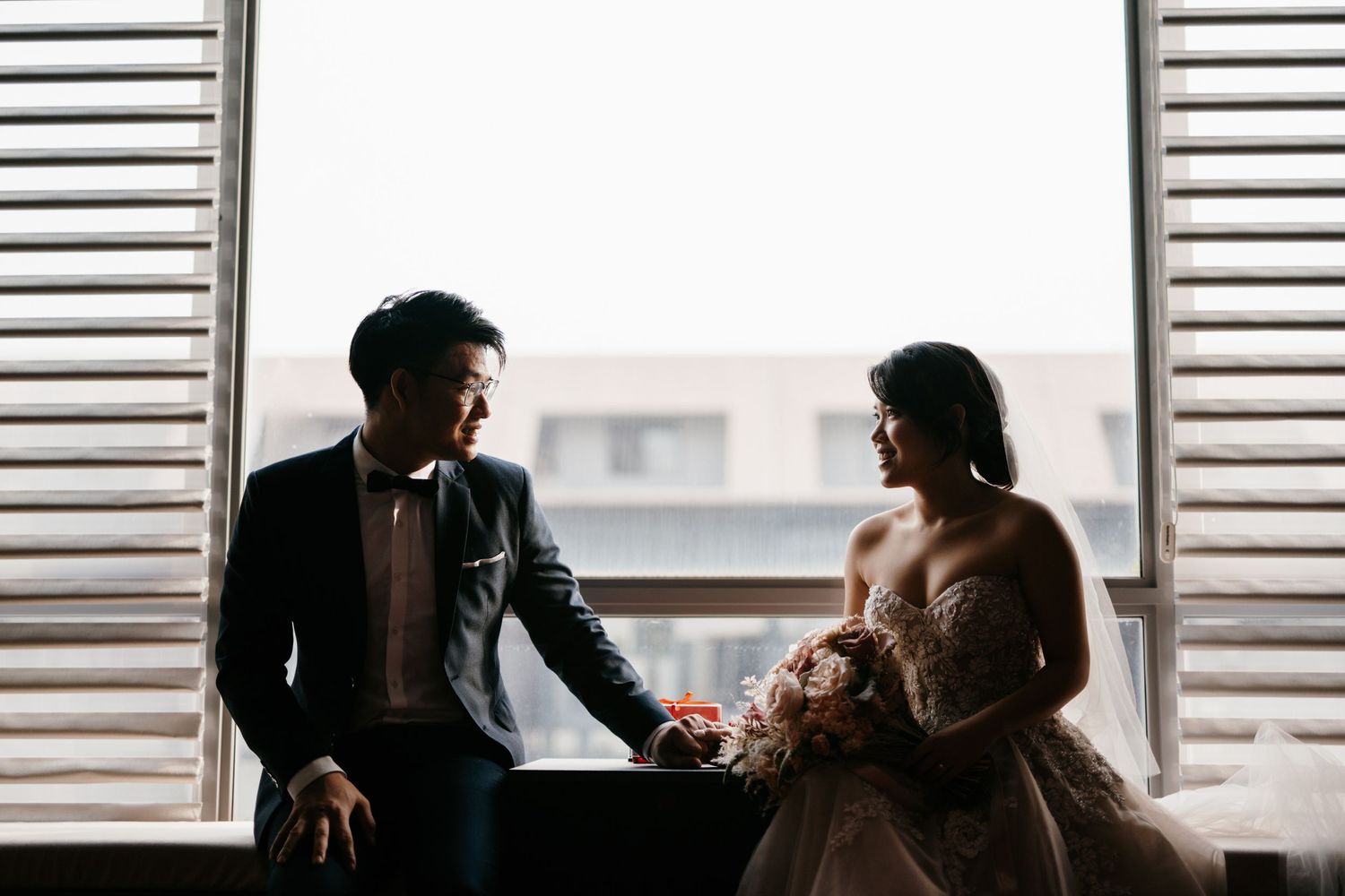 Silhouettes against bright windows create dramatic wedding day composition.