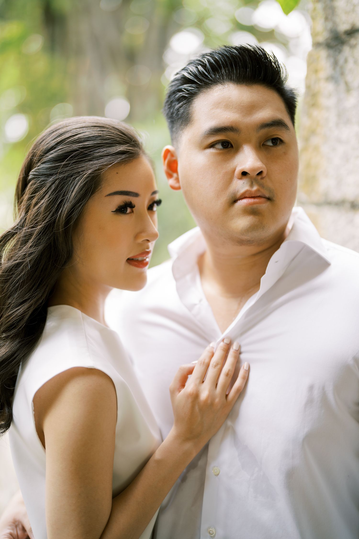 Intimate portrait of a couple in white clothing against a bright natural background.