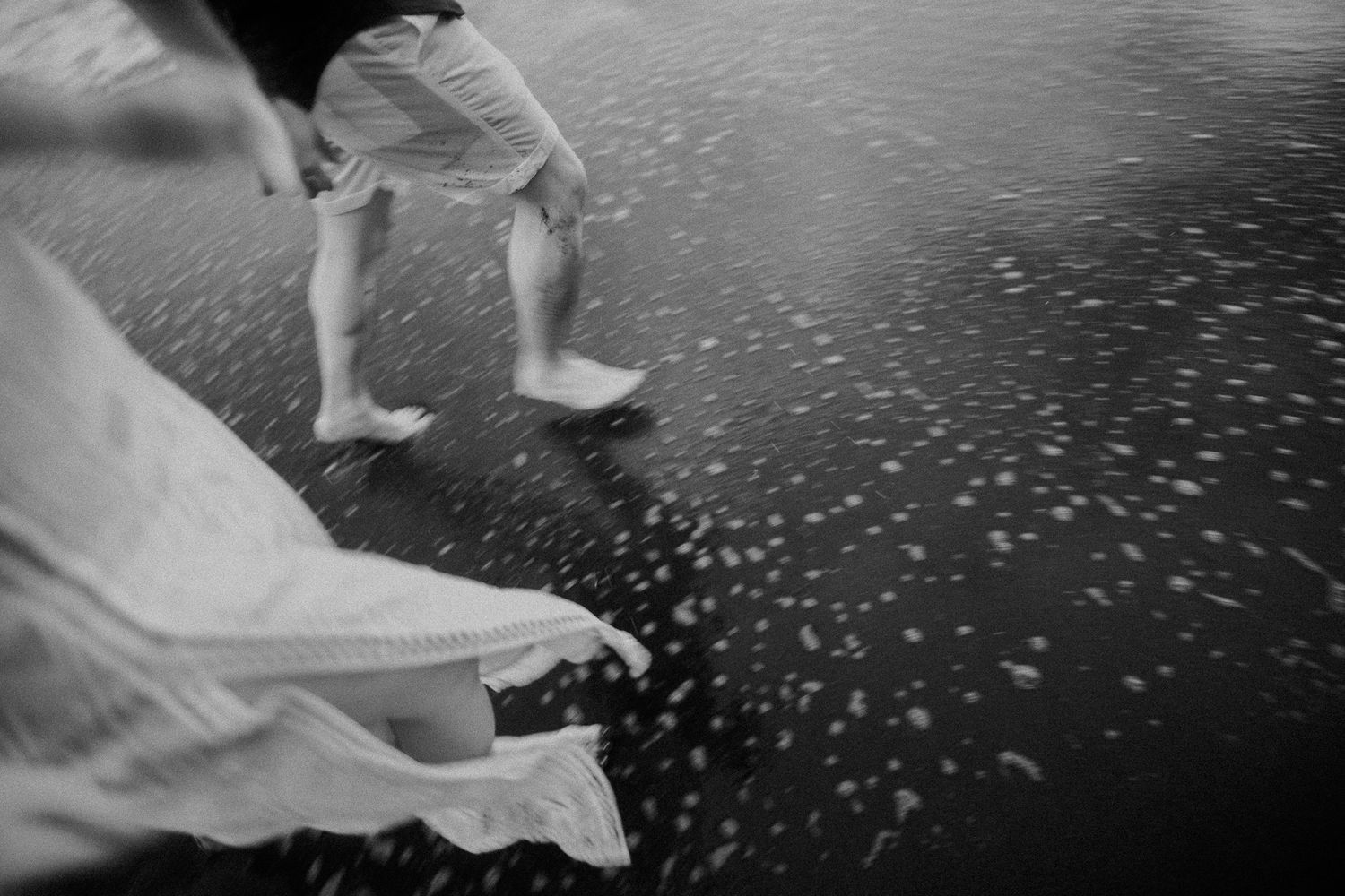 Couple strolling on a beach with scattered seashells at golden hour.