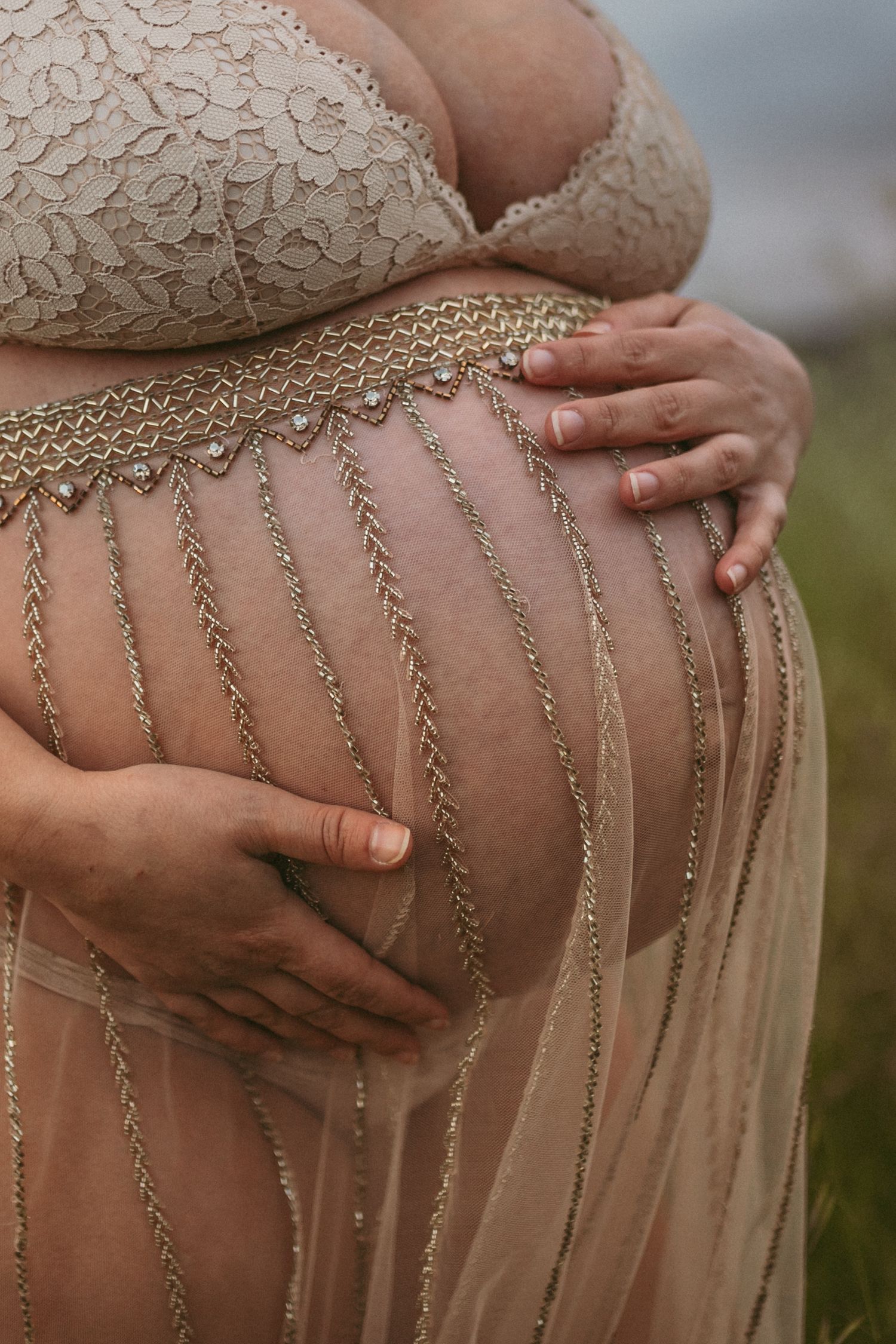 A pregnant belly with a lace skirt, photographed by Kristy Baker Photography.
