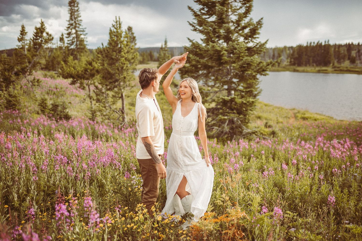 A couple dancing in a field of purple wildflowers by a lake, photographed by Kristy Baker Photography in Steamboat Springs, Colorado.