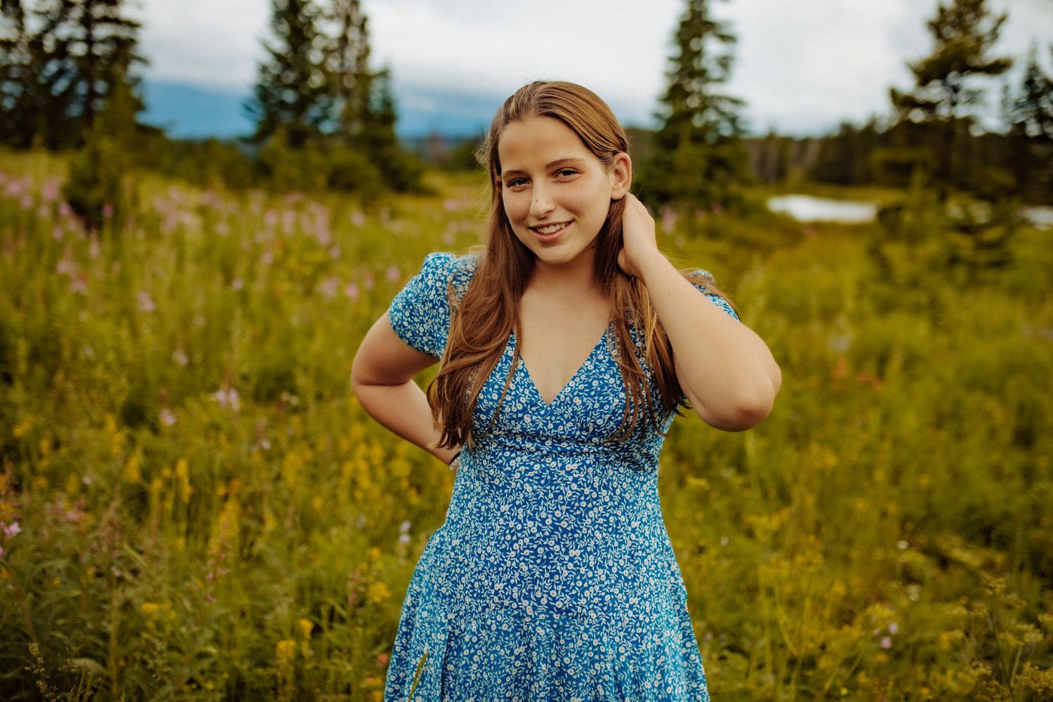 A high school senior girl wearing a blue floral dress poses for the camera.