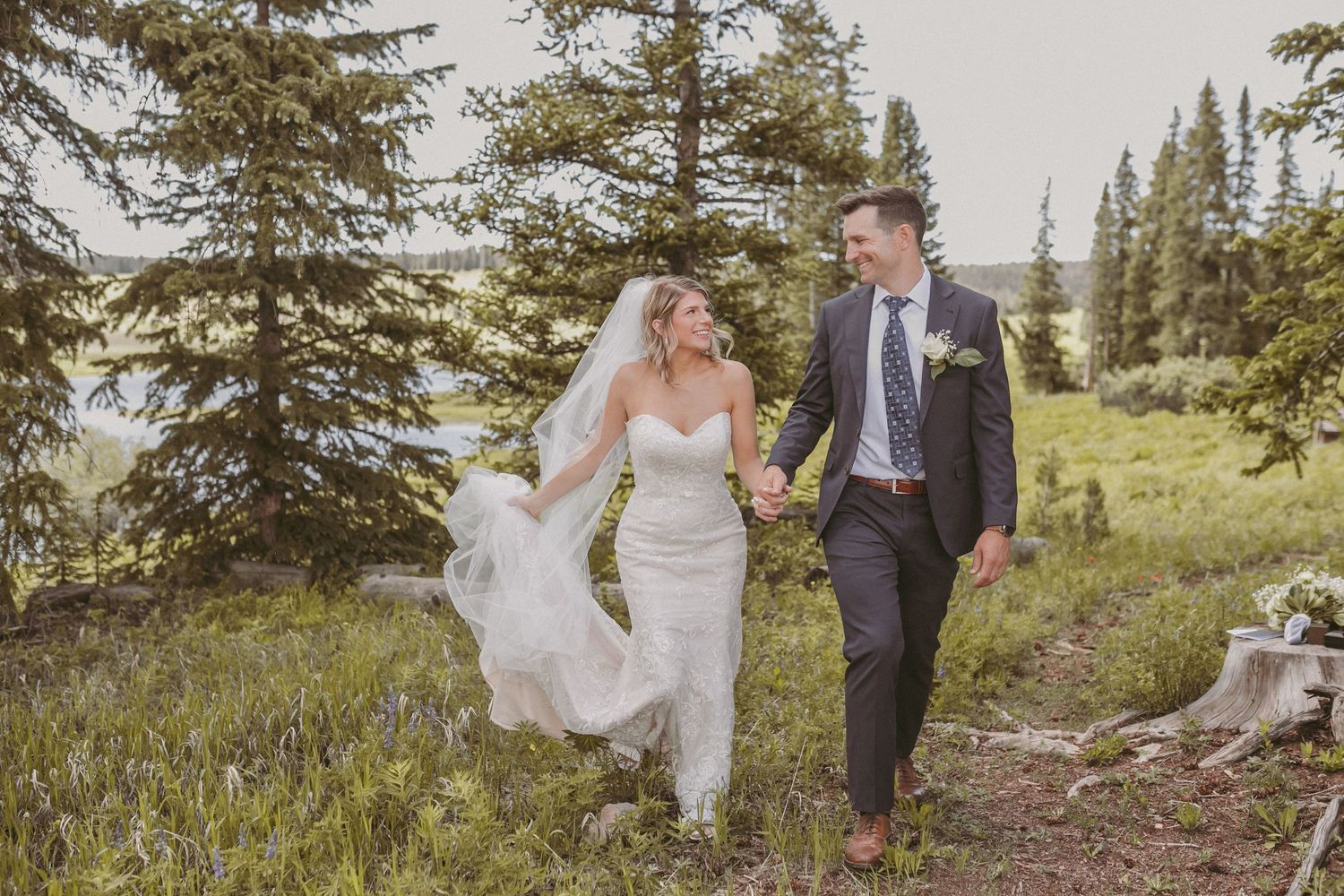 A just married couple walking and holding hands with smiles on their faces, photographed by Kristy Baker Photography.