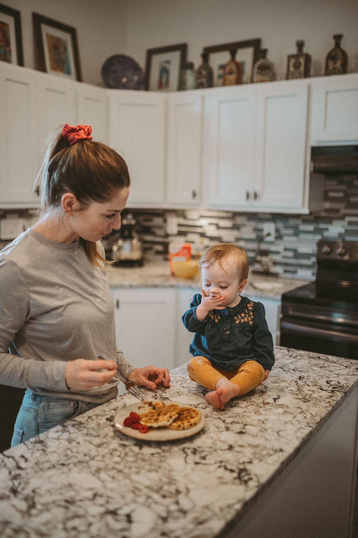 A mother and young daughter eat waffles together in the kitchen, photographed by Kristy Baker Photography in Steamboat Springs, CO.