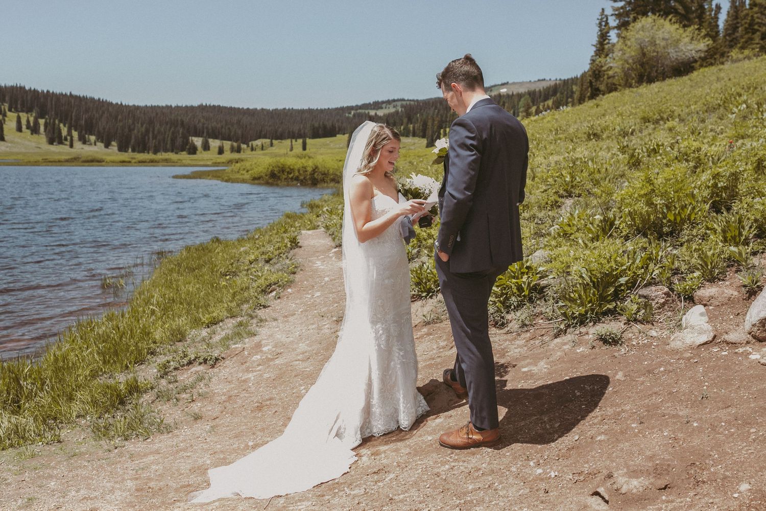 A bride standing by water reading her vows to the groom, photographed by Kristy Baker Photography in Steamboat Springs, Colorado.