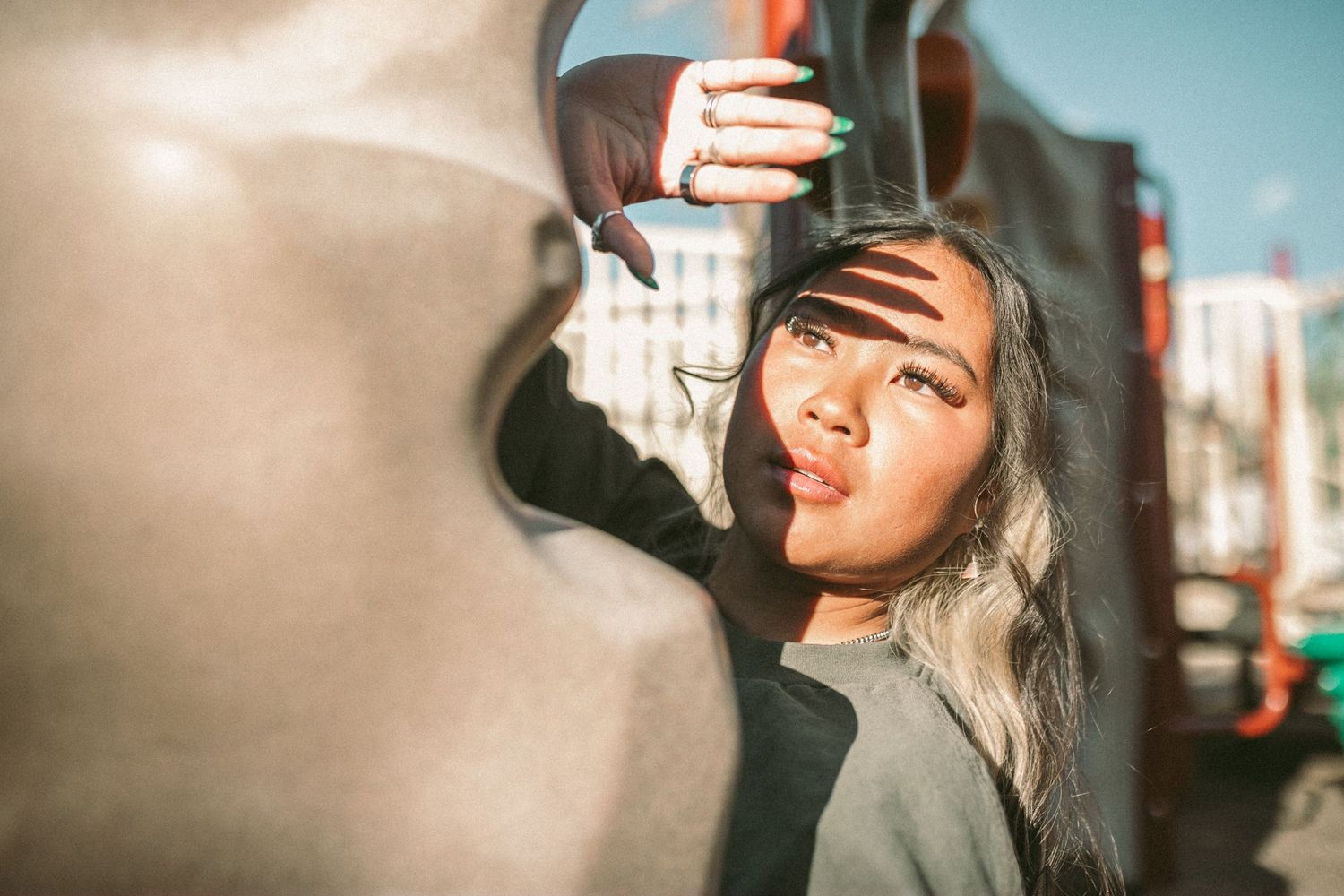 A woman shields her face from the sun with her hand and the shadow of her fingers is displayed across her face.