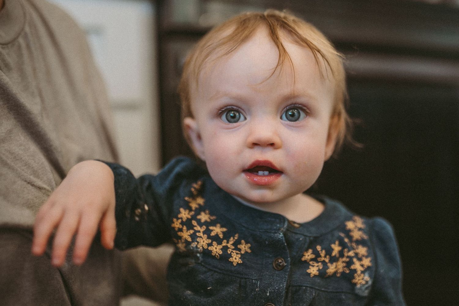 Little girl in a denim shirt with yellow flowers stares at the camera, photographed by Kristy Baker Photography in Steamboat Springs, CO.