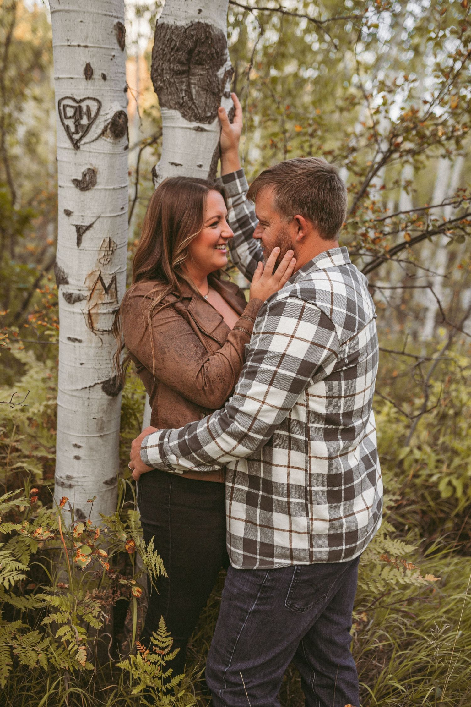 A couple leaning against an aspen tree in the fall, photographed by Kristy Baker Photography in Steamboat Springs, Colorado.