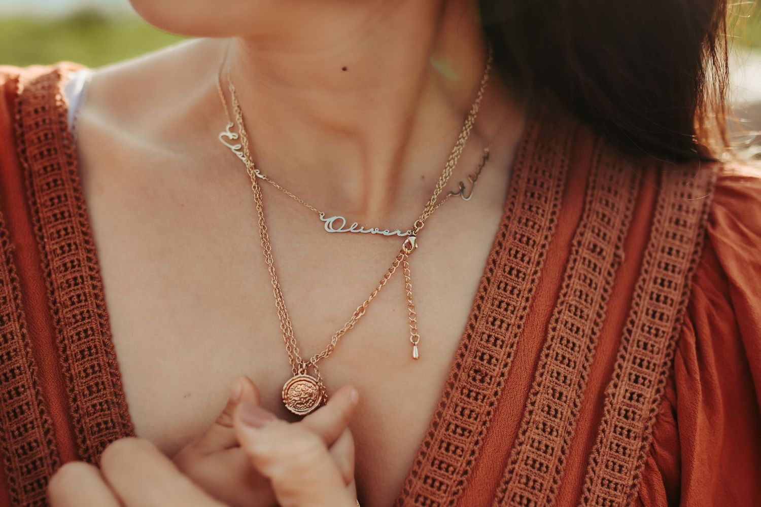 A mother reaches for her necklace that has all of her children's names on it, photographed by Kristy Baker Photography.