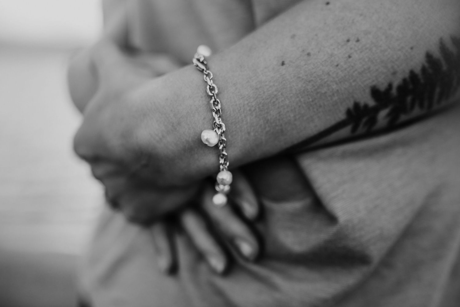 A pearl bracelet on the wrist of a woman embracing her husband, photographed by Kristy Baker Photography in Steamboat Springs, Colorado.