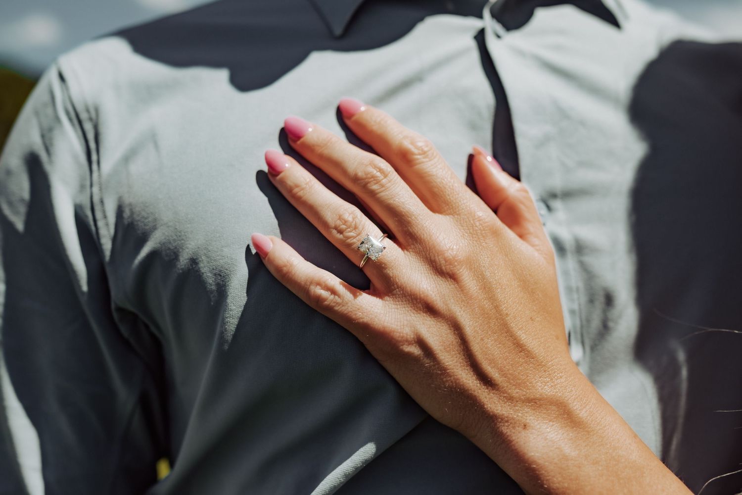 A woman wearing a diamond ring lays her hand on her husband's chest, photographed by Kristy Baker Photography.