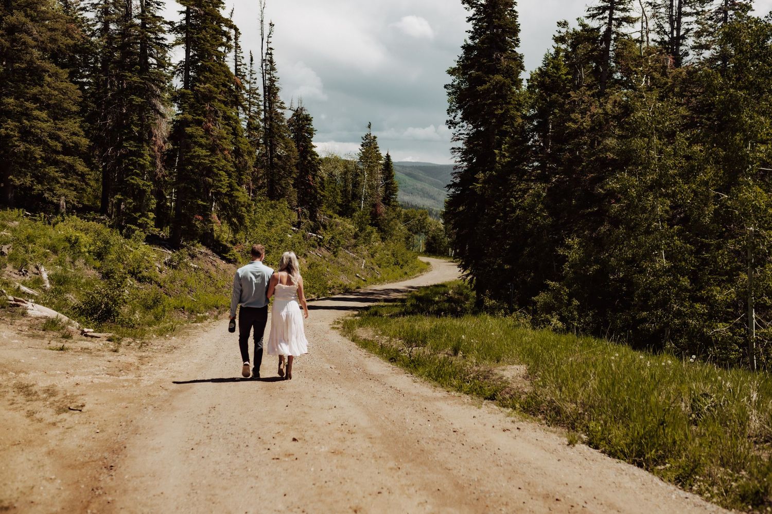 A couple walking away from the camera down a long dirt road, photographed by Kristy Baker Photography in Steamboat Springs, Colorado.