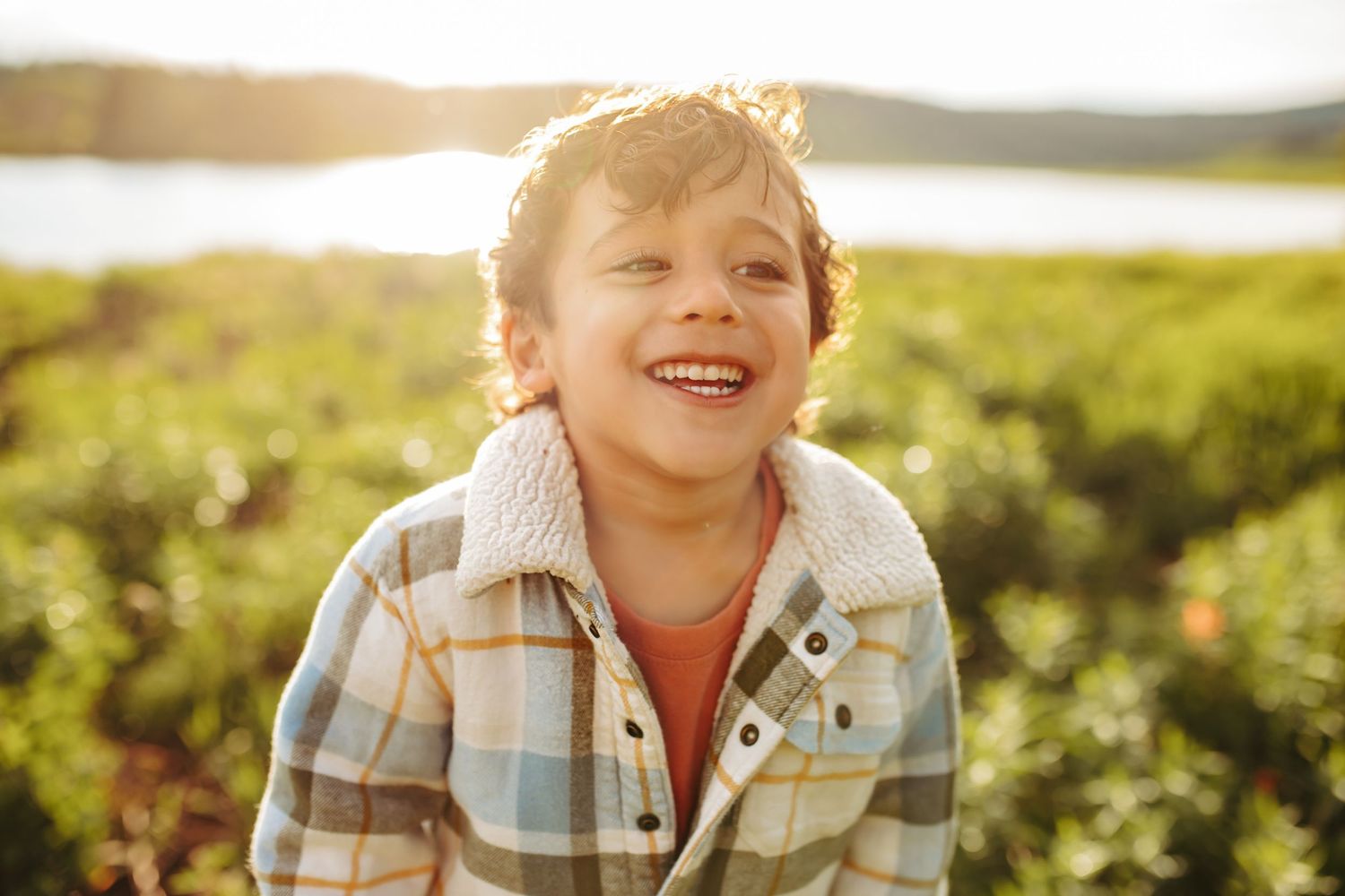 A young boy is smiling and laughing, photographed by Kristy Baker Photography.