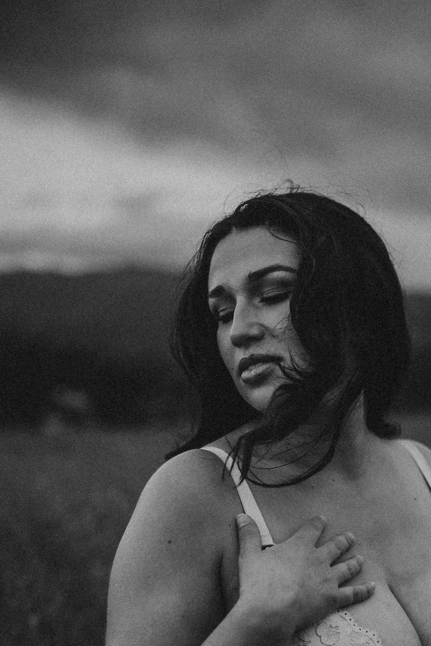 A woman's hair blows in the wind as she looks down, photographed by Kristy Baker Photography.