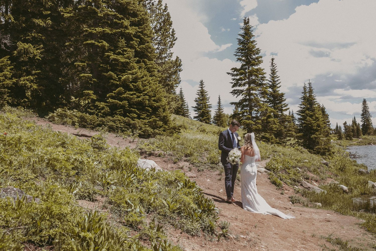 A groom standing by pine trees reading his vows to his bride, photographed by Kristy Baker Photography in Steamboat Springs, Colorado.