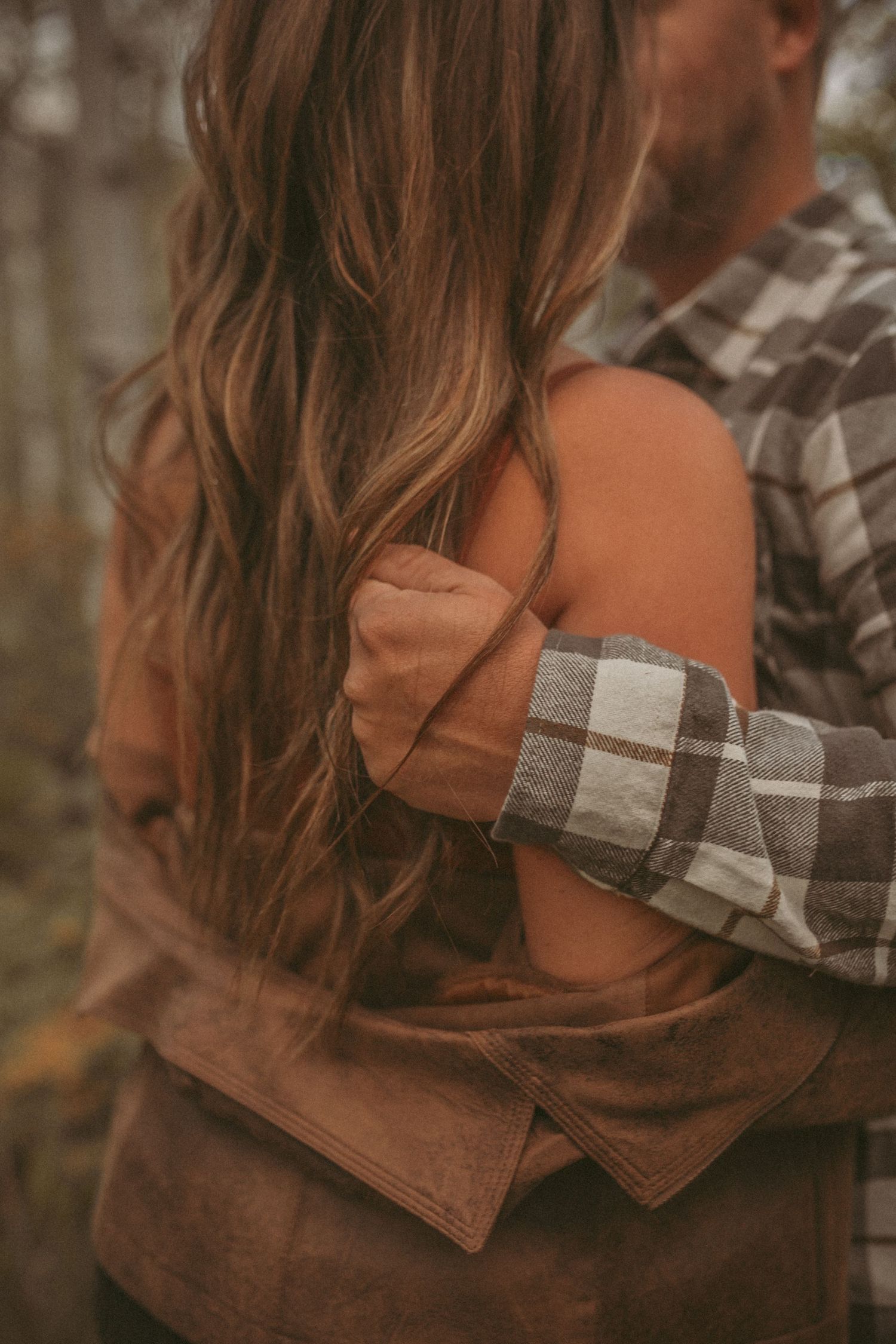 A man holds onto his wife's hair while they embrace each other, photographed by Kristy Baker Photography in Steamboat Springs, Colorado.