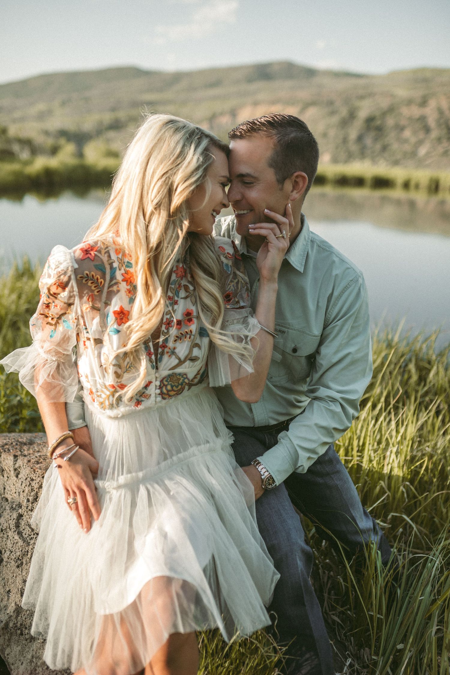 A couple sit together and lean into each other while smiling, photographed by Kristy Baker Photography in Steamboat Springs, Colorado.