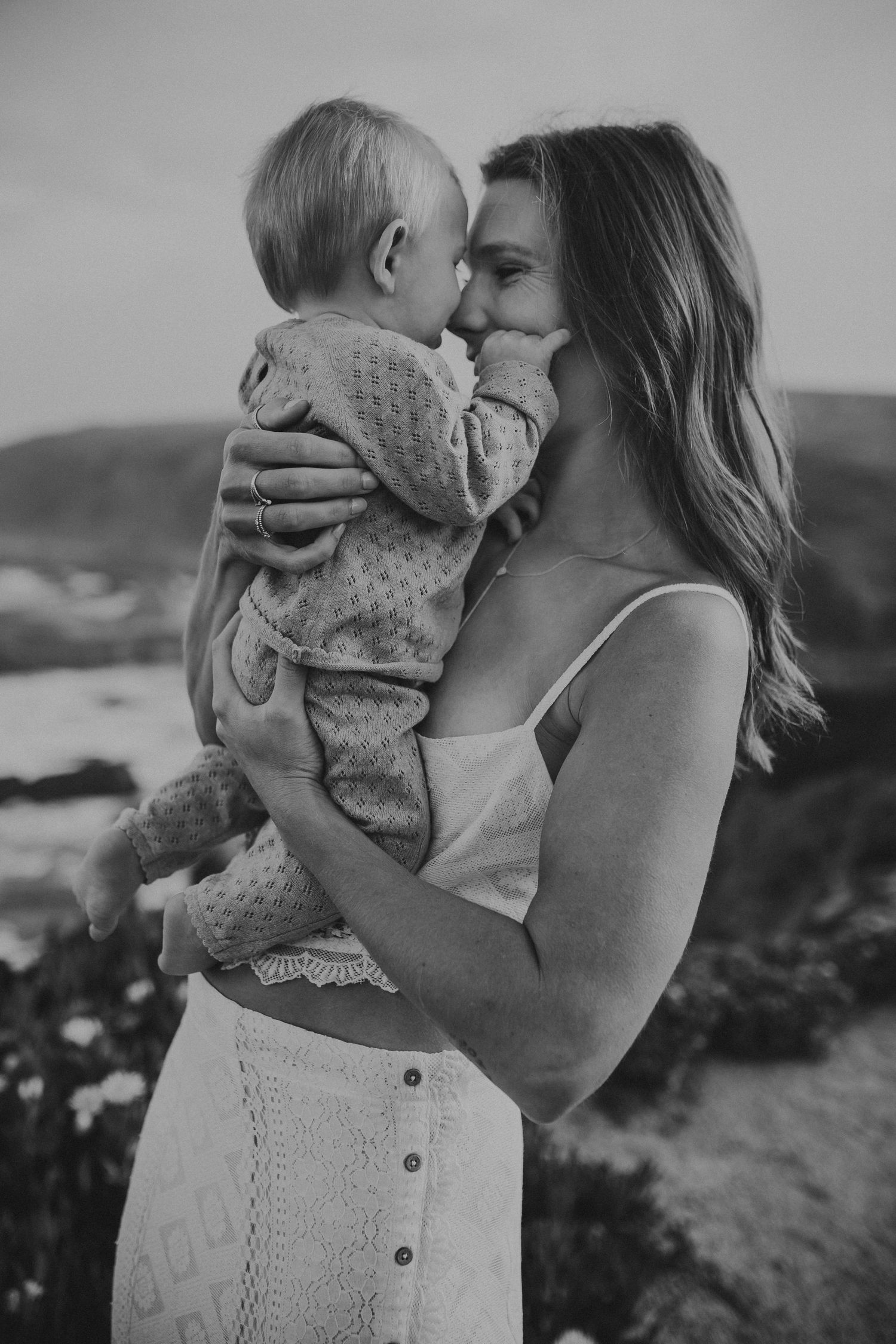 A mother holds her young son in her arms and they touch foreheads, photographed by Kristy Baker Photography.