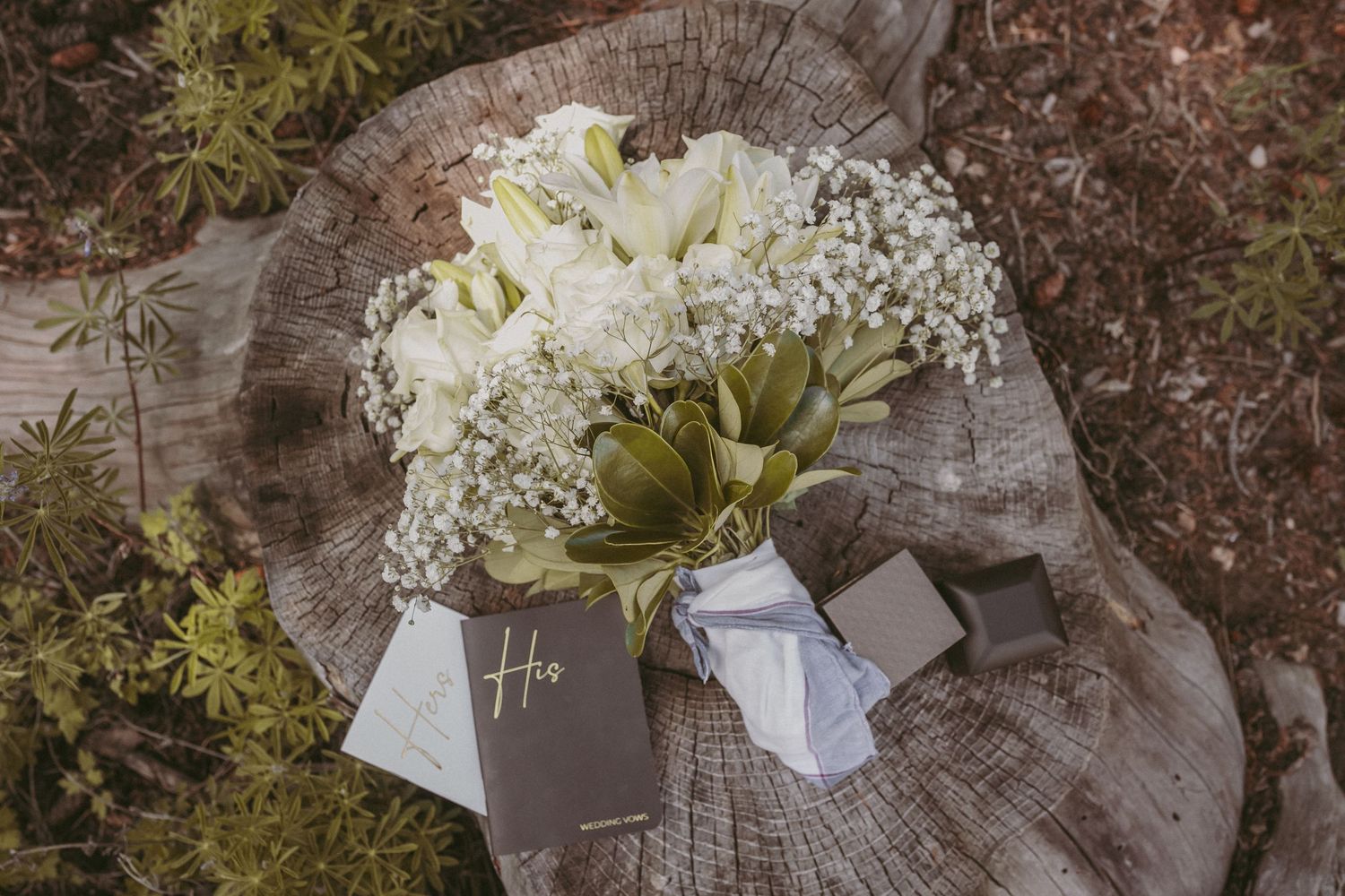 A bride's white rose bouquet lays next to her and her husband's vow books, photographed by Kristy Baker Photography.