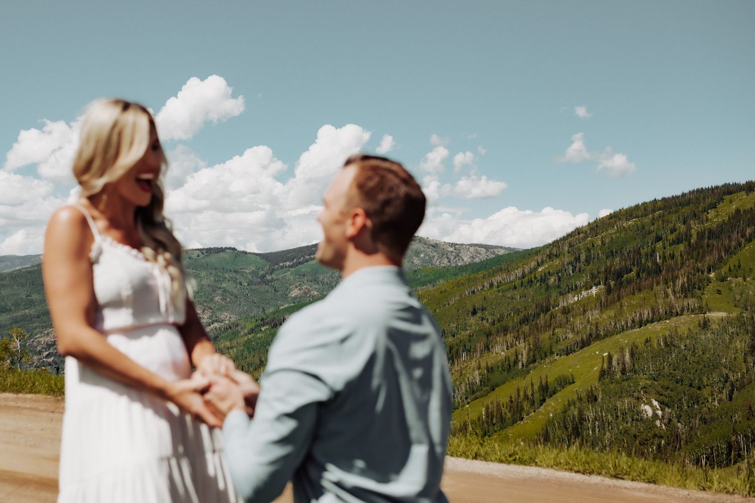 A man on his knee proposing to his girlfriend with mountains in the background, photographed in Steamboat Springs, Colorado.