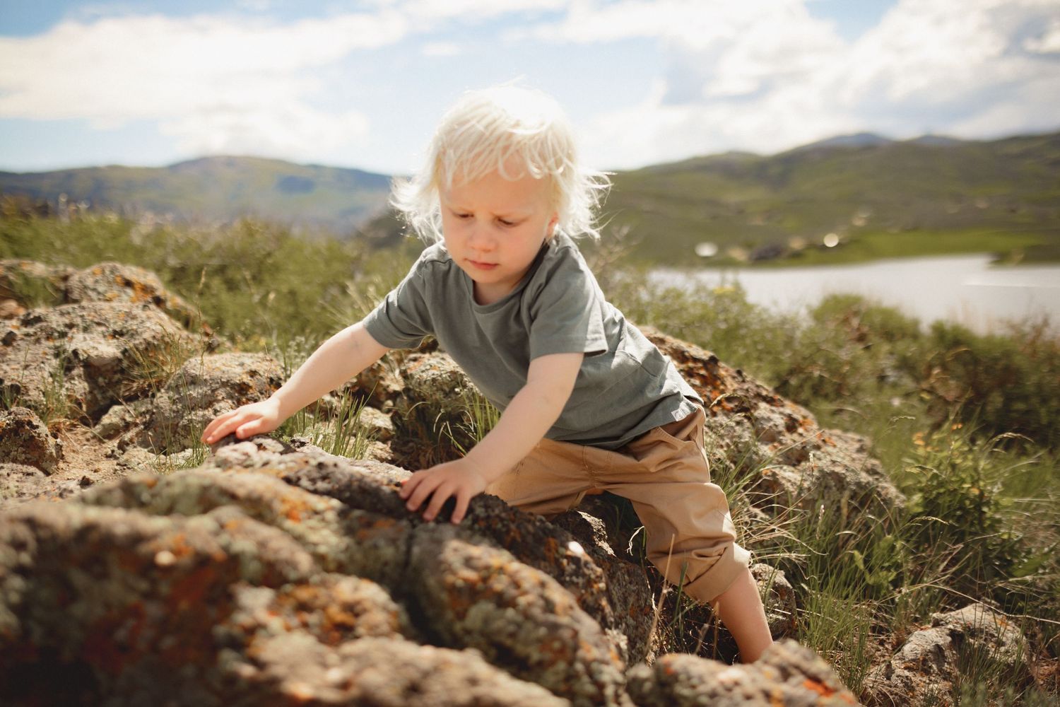 A small boy climbs over some rocks on a mountain, photographed by Kristy Baker Photography in Steamboat Springs, Colorado.