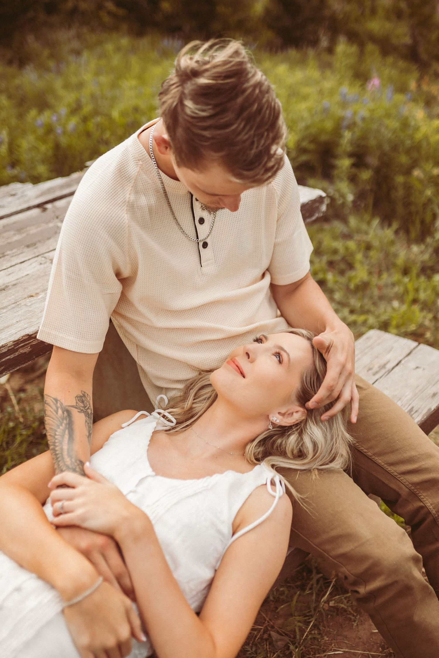 A man cradling his girlfriend in his lap as he looks down at her, photographed by Kristy Baker Photography in Steamboat Springs, Colorado.