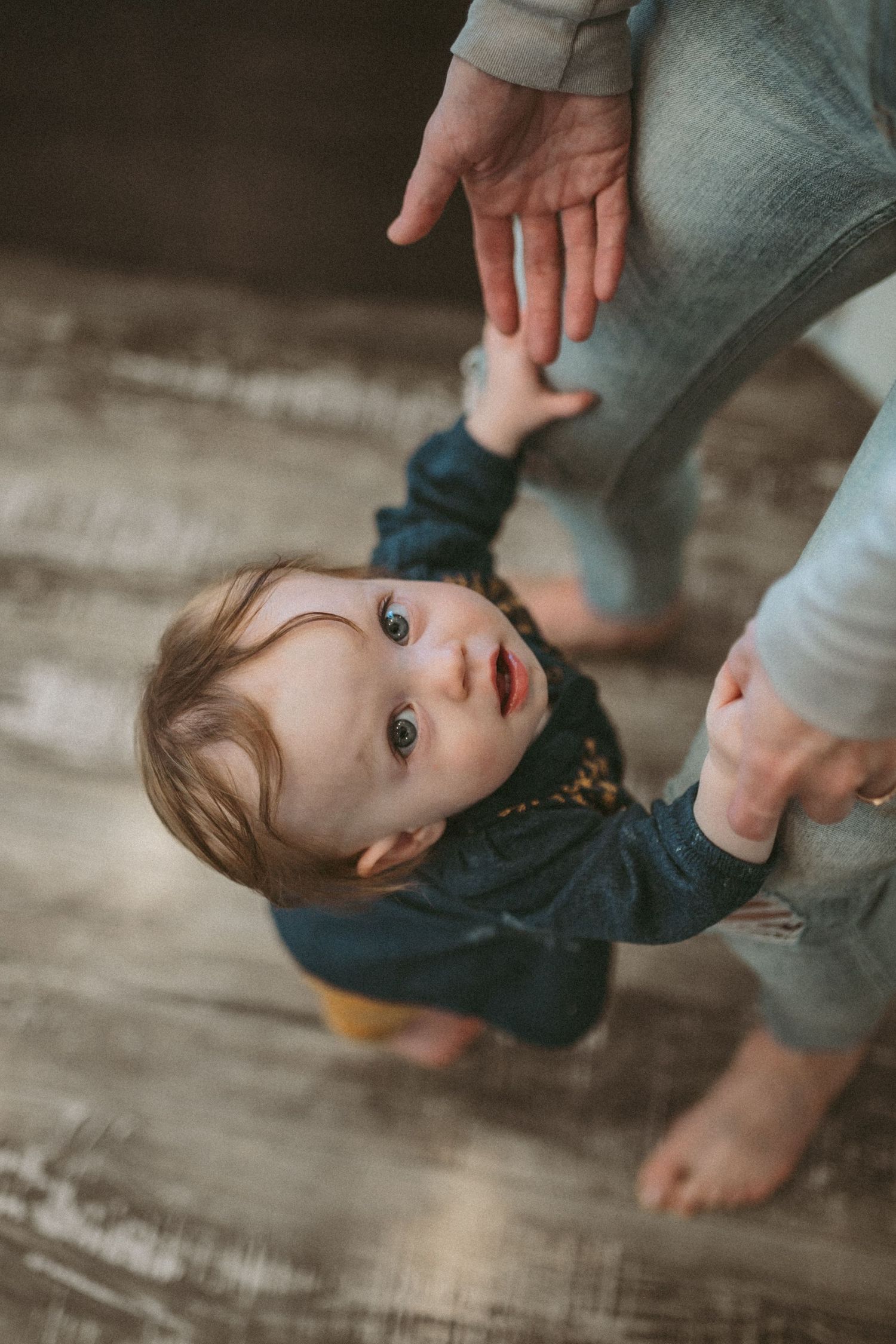 A toddler girl is looking up and reaching for her mother's hands, photographed by Kristy Baker Photography in Steamboat Springs, CO.