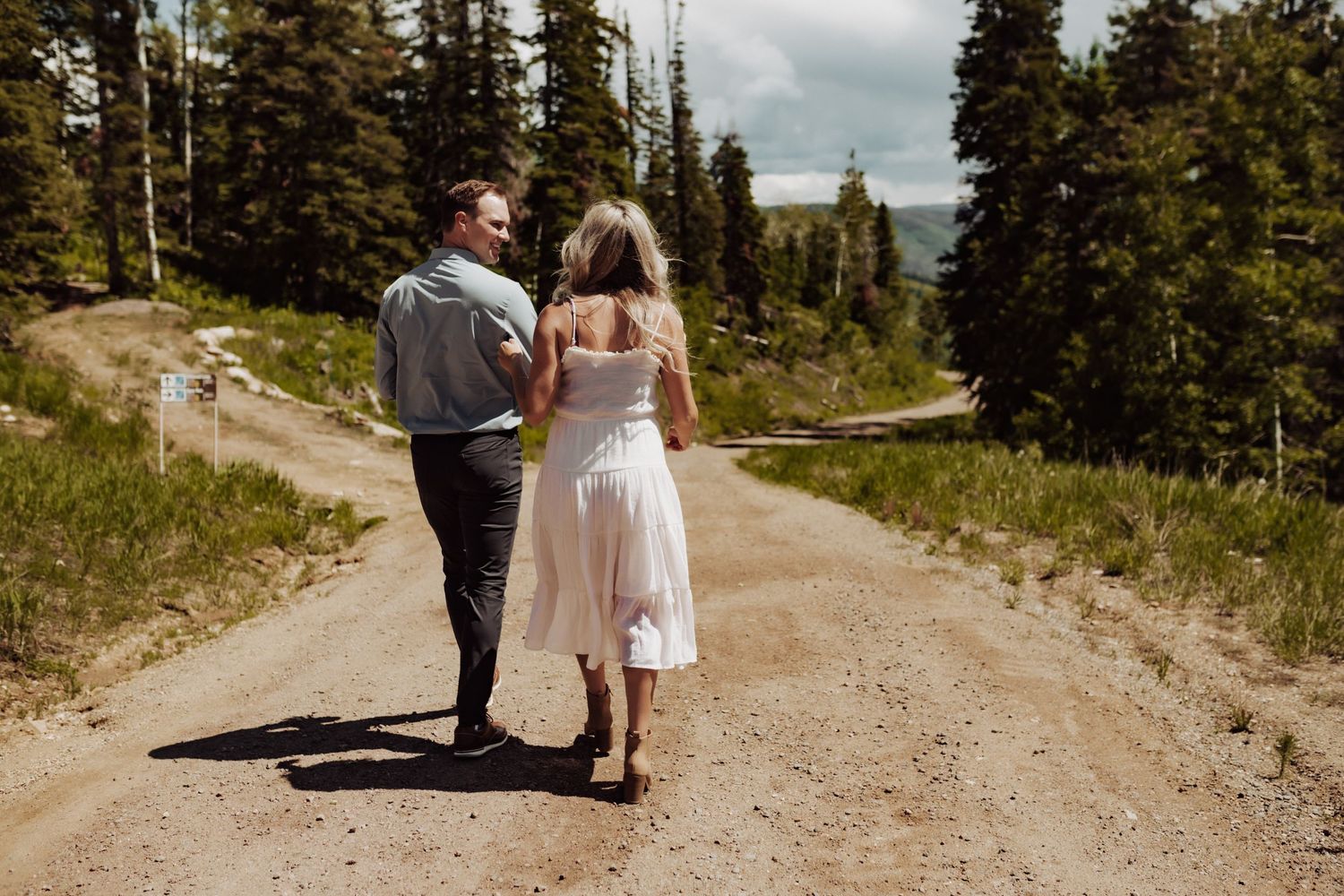 A couple walking away from the camera down a dirt road, photographed by Kristy Baker Photography in Steamboat Springs, Colorado.