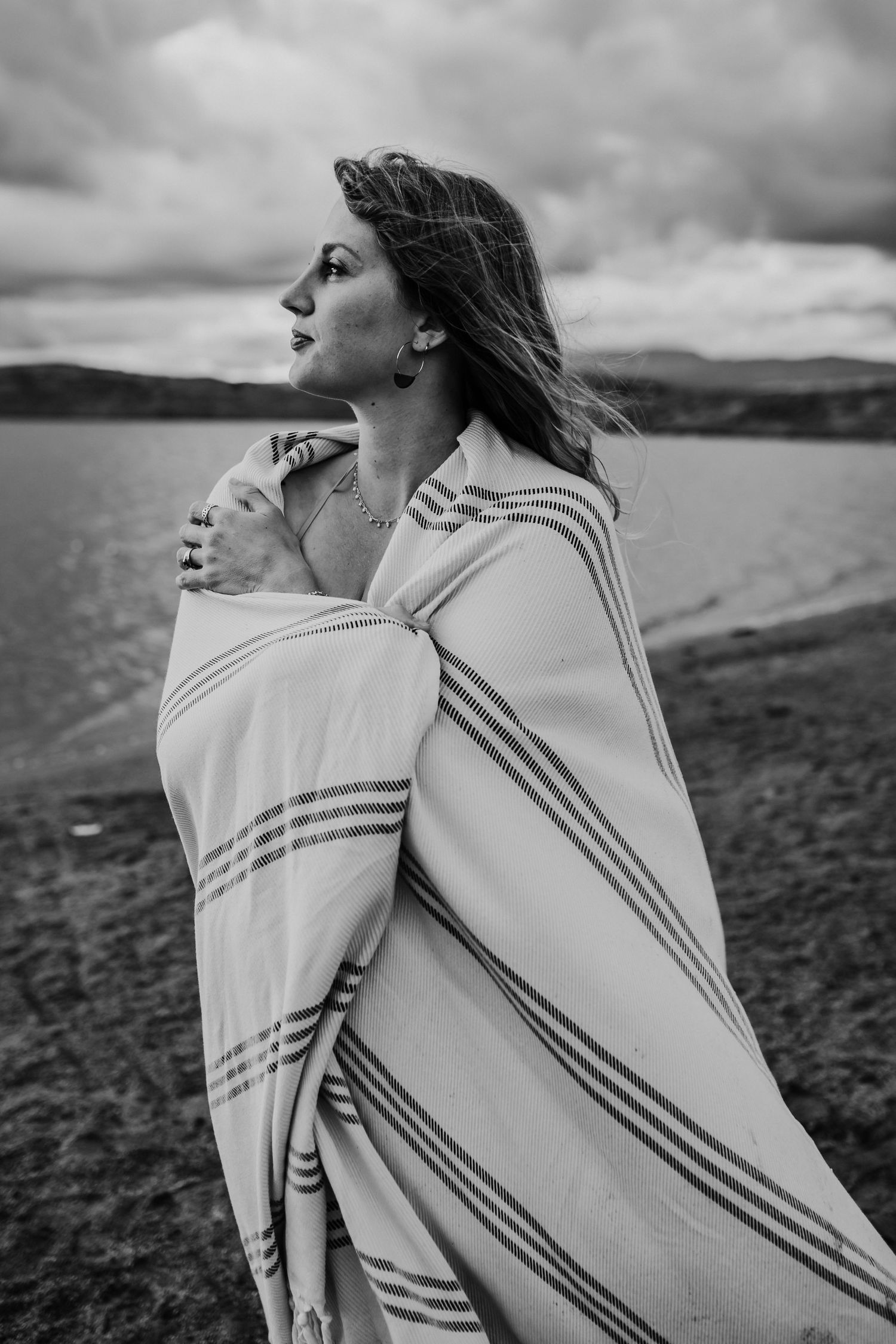 A woman wrapped in a blanket looking out at the water, photographed by Kristy Baker Photography in Steamboat Springs, Colorado.