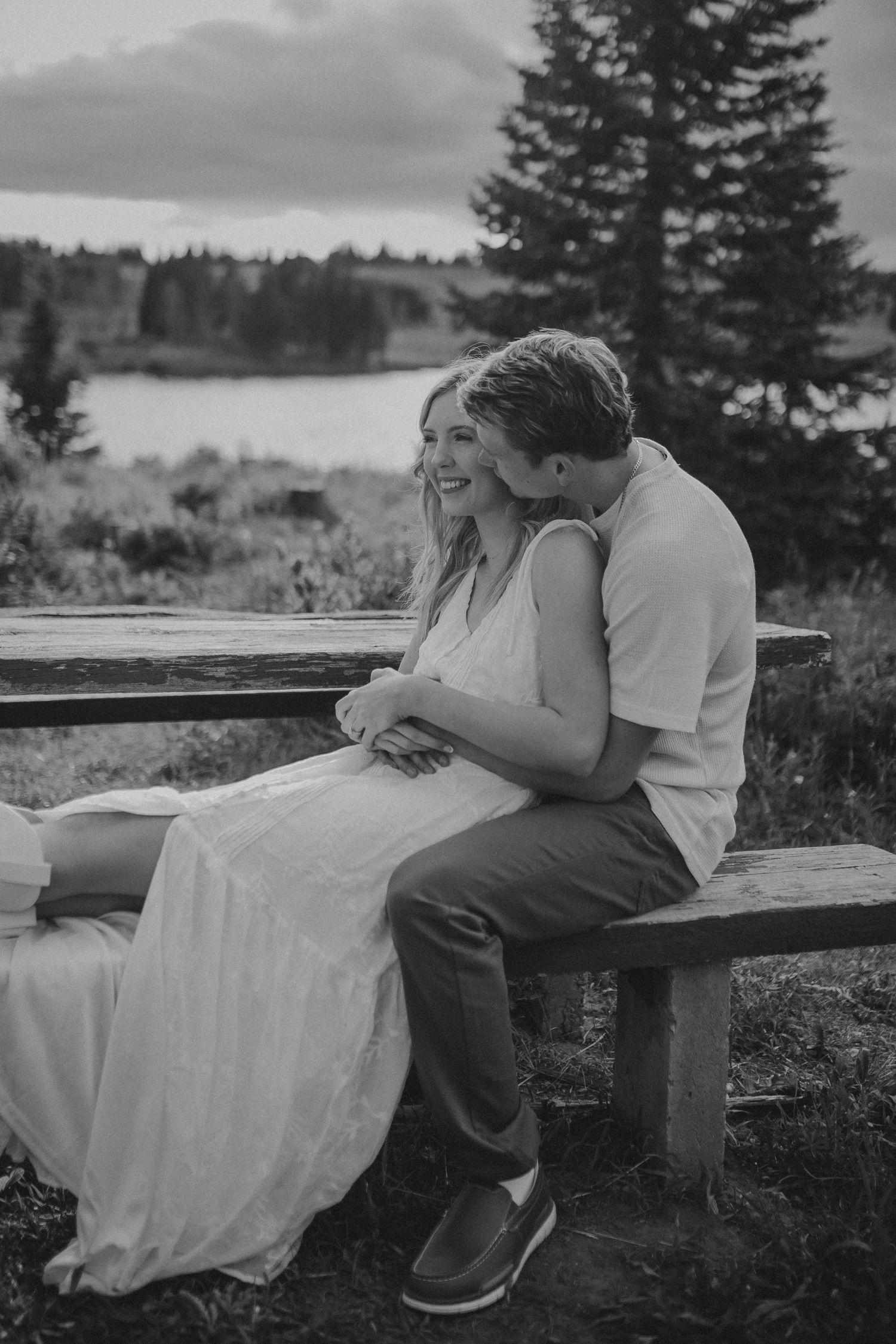 A couple sitting on a picnic bench and leaning into each other, photographed by Kristy Baker Photography in Steamboat Springs, Colorado.