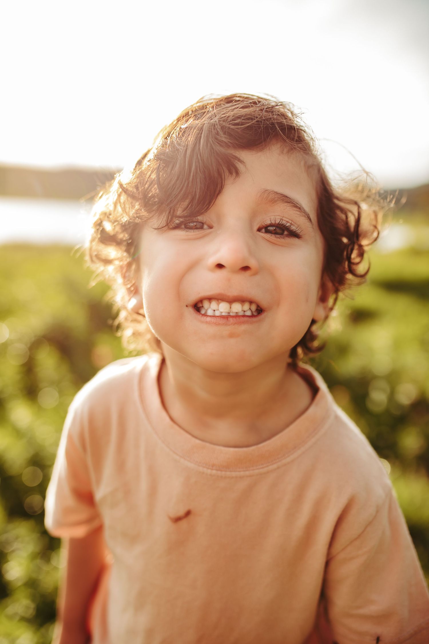 A young boy smiles big for the camera, photographed by Kristy Baker Photography.