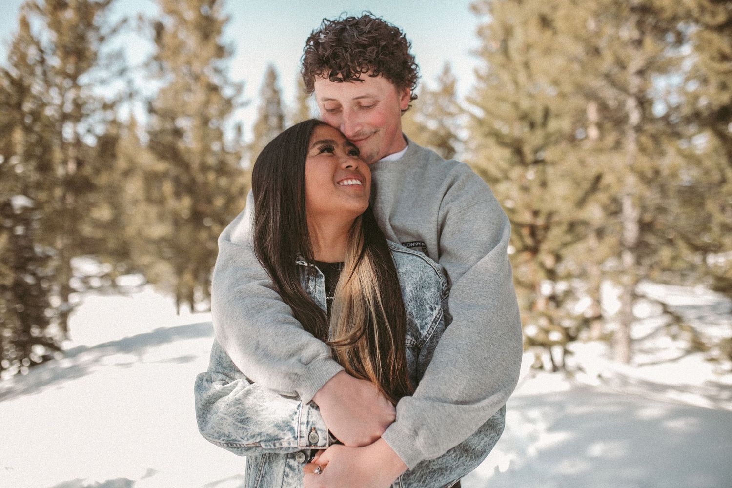 A couple embracing each other in a forrest during the winter, photographed by Kristy Baker Photography in Steamboat Springs, Colorado.
