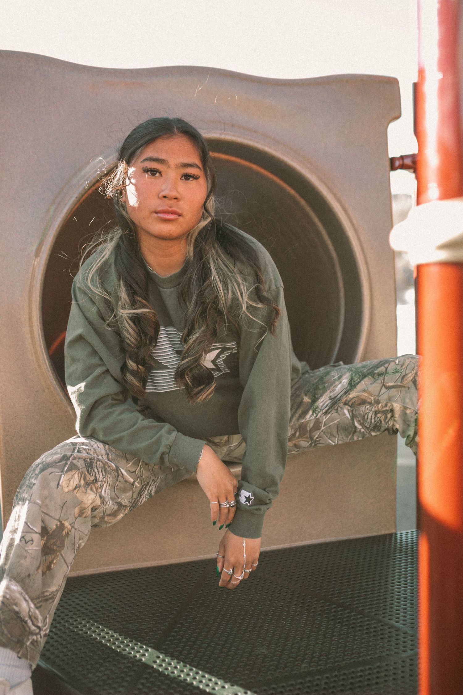 A woman sits at the entrance to a slide at the park.