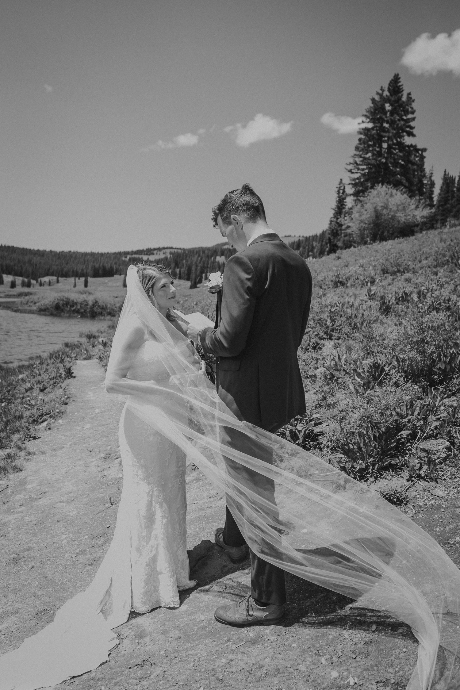 A groom standing by the water reading his vows to his bride, photographed by Kristy Baker Photography in Steamboat Springs, Colorado.