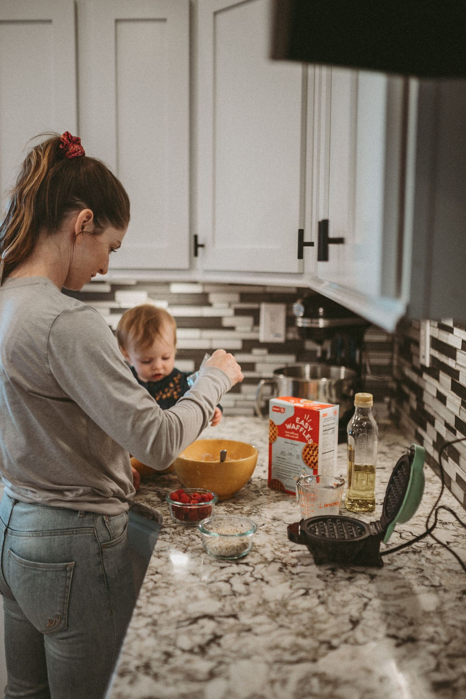 A mother and young daughter make waffles in the kitchen together, photographed by Kristy Baker Photography in Steamboat Springs, CO.