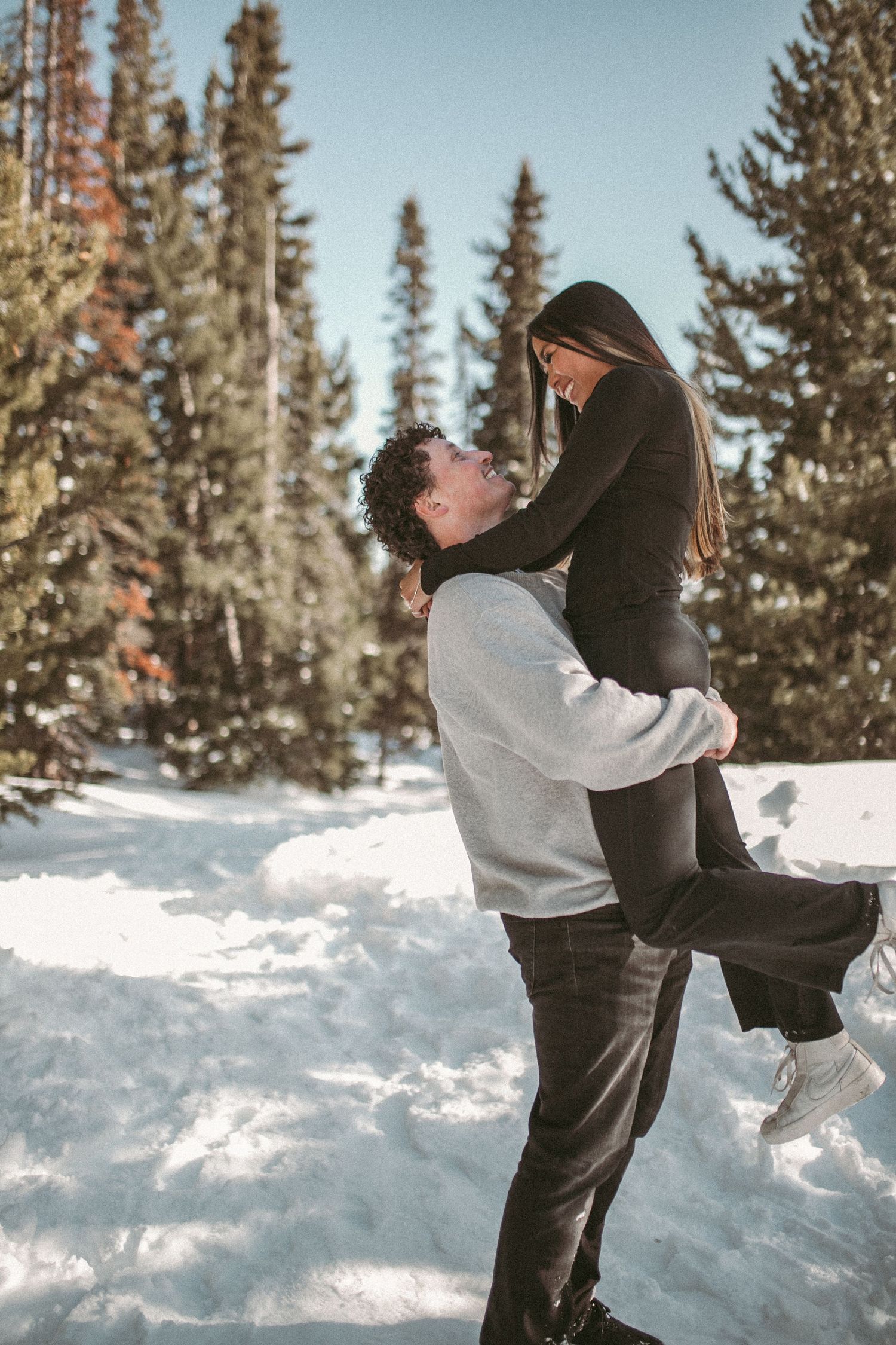 A man holding up his girlfriend and looking up at her, photographed by Kristy Baker Photography in Steamboat Springs, Colorado.